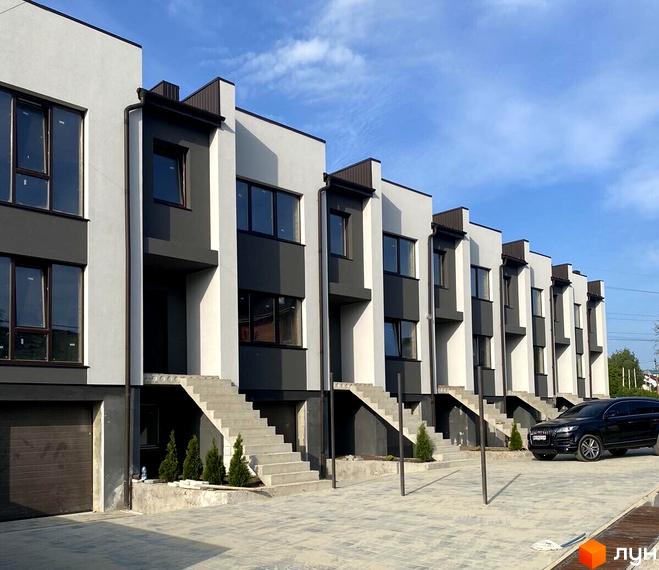 Вигляд фасаду будинку на вулиці Петриківська, 12. На передньому плані прибудинкова територія з тротуарною плиткою.