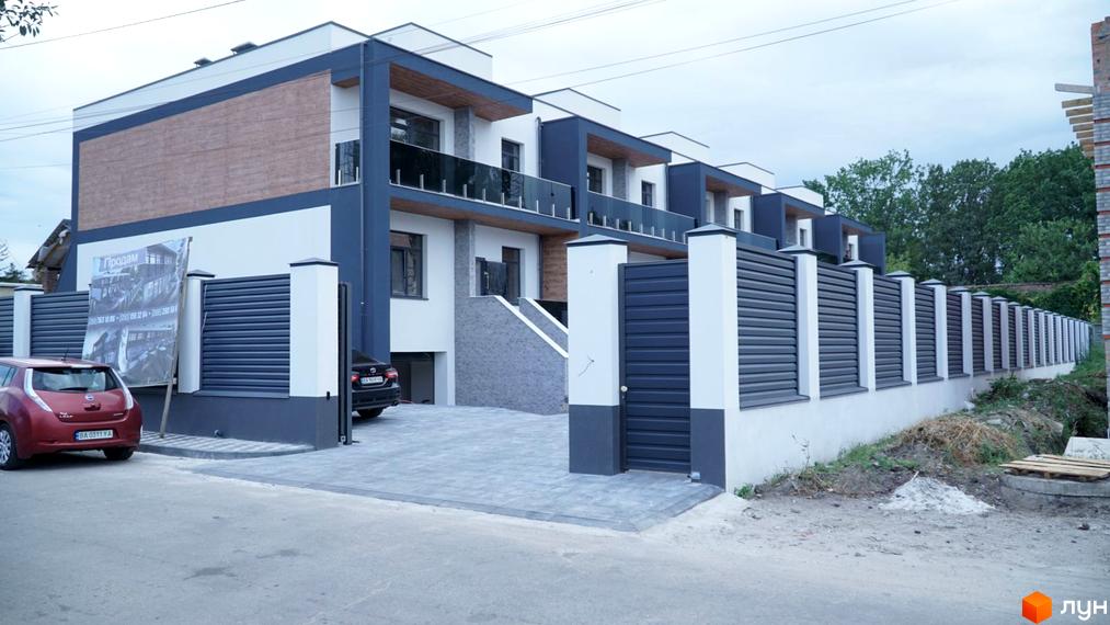 Зображення житлового комплексу на вулиці Куроп'ятникова, 56. На фото видно фасад будинку та прибудинкову територію з парканом.