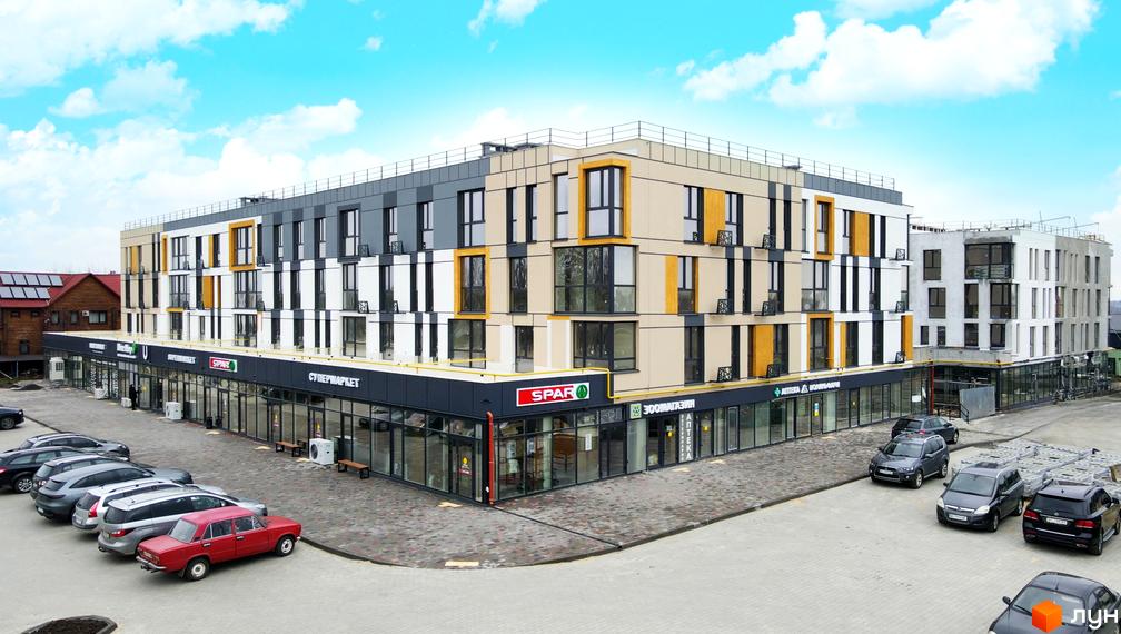 Житловий комплекс U HOME з комерційними приміщеннями на першому поверсі та фасадом світлих тонів. Прилегла територія обладнана парковкою.