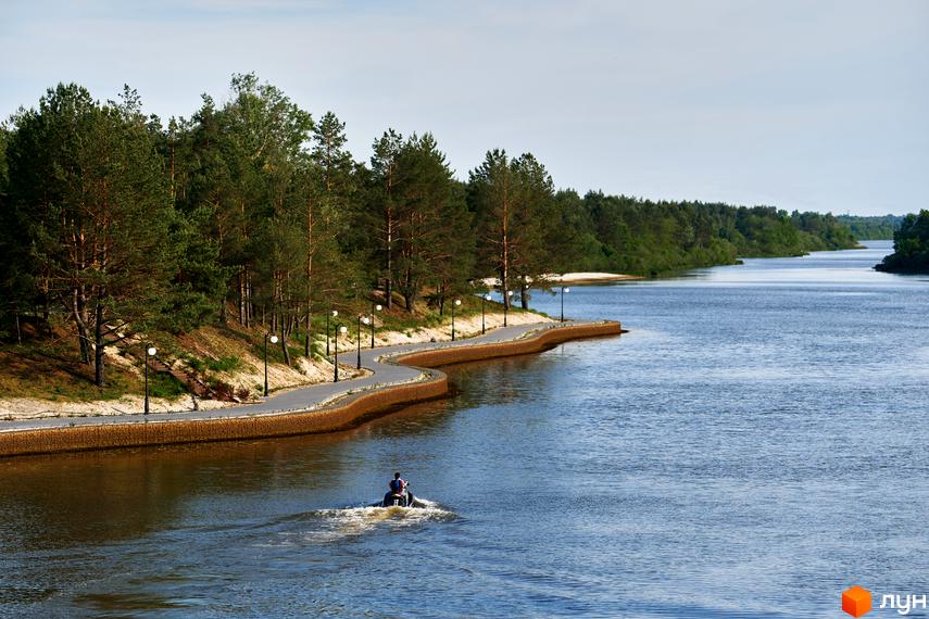 Фото Котеджного містечка Riviera Village з річкою та набережною. Вигляд на водний транспорт, берегову лінію з деревами та ліхтарями.