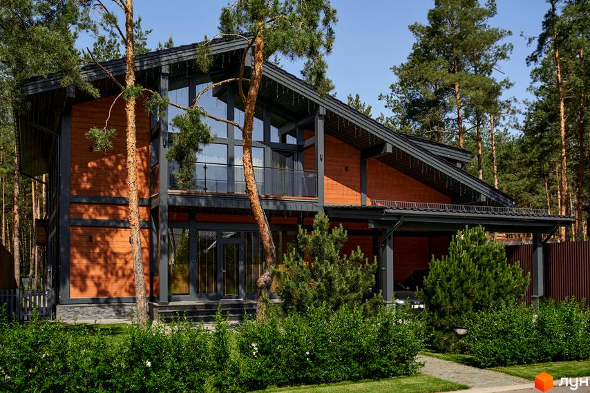 Зображення будинку в Котеджному містечку Riviera Village. Двоповерховий будинок з дерев'яним фасадом, великими вікнами та зеленим газоном.
