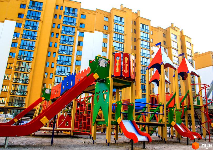 Житловий комплекс Щасливий на Петропавлівці. Сучасний житловий будинок з яскравим дитячим майданчиком на прибудинковій території.