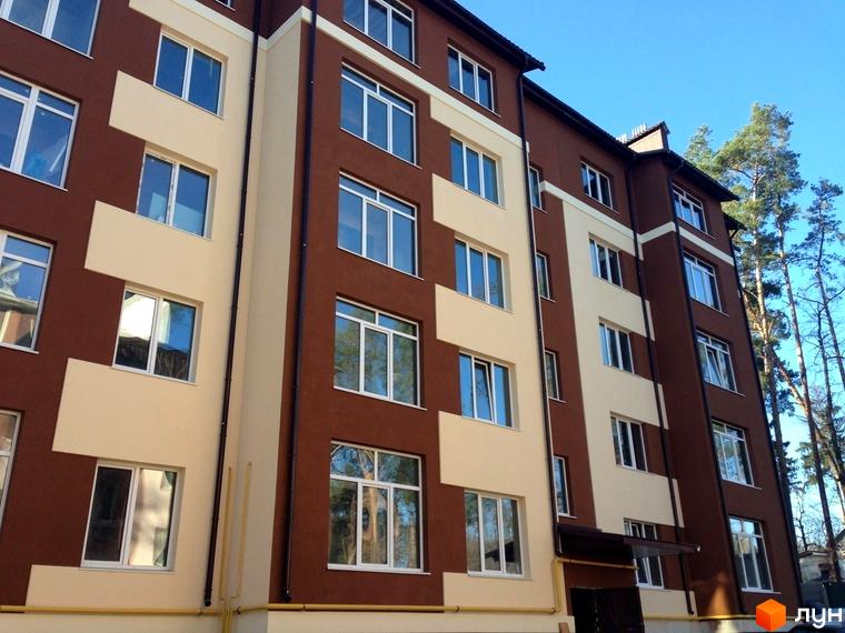 Новобудова на вул. Лермонтова, 6е. Фасад будинку двоколірний, коричнево-бежевий, з великою кількістю вікон. Поруч ростуть дерева.