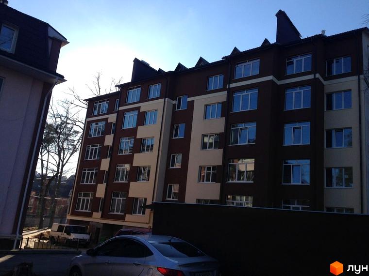 Зовнішній вигляд новобудови на вул. Лермонтова, 6е. Багатоповерховий будинок з коричнево-бежевим фасадом та великими вікнами. На передньому плані видно автомобіль та частину прибудинкової території.