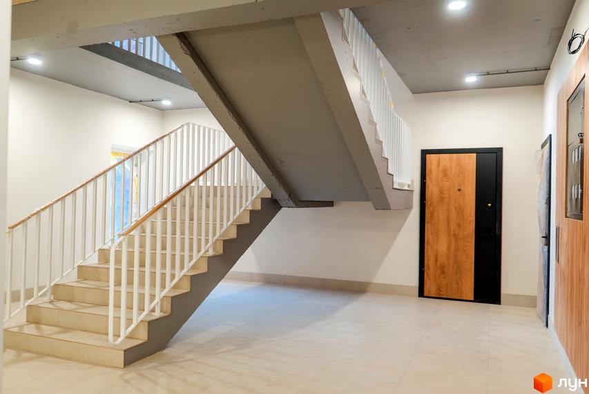 Сходи в новому будинку ЖК Долішній з білими перилами та світлими стінами. Просторий хол з дверима та підлогою з плитки.