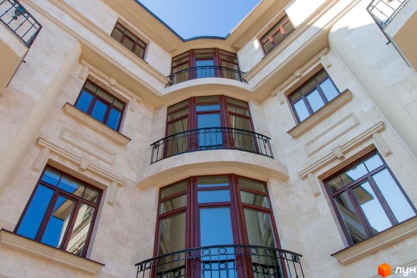 Клубний будинок Ліон. Фасад новобудови з великими вікнами та балконами, виконаний з світлого каменю. Будинок має вигнуту форму, що створює затишний внутрішній двір.