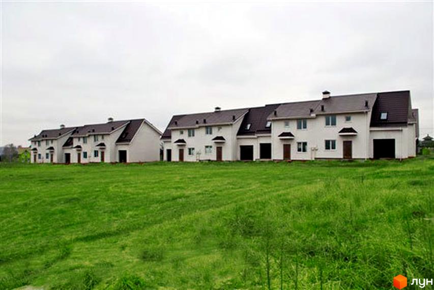 Котеджне містечко КМ Затишний Двір: білі двоповерхові будинки з темними дахами та зелена галявина перед ними. Навколо новобудов доглянута територія.