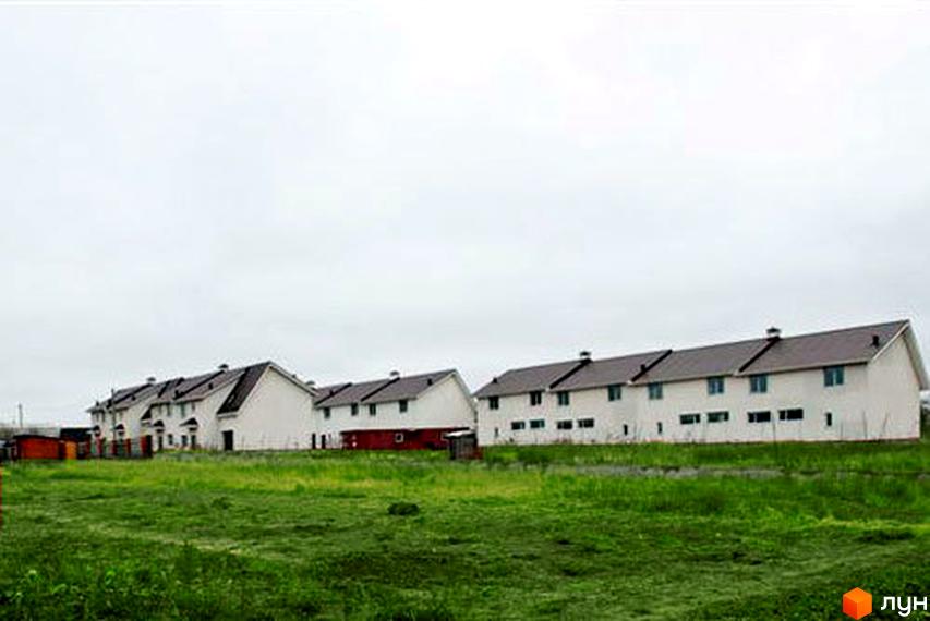 Котеджне містечко Затишний Двір: ряд білих будинків з темними дахами на тлі зеленого поля. Ознайомтеся з новобудовою.