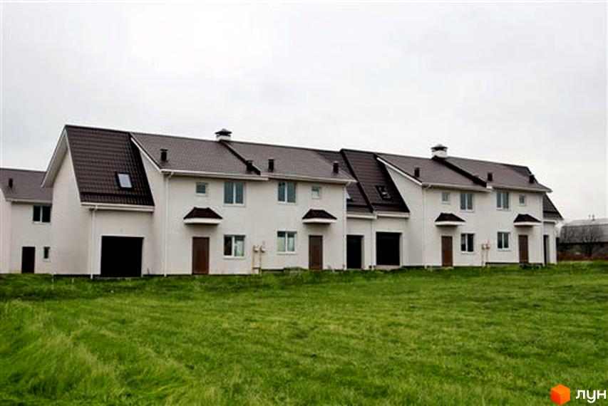 Котеджне містечко Затишний Двір: білі двоповерхові будинки з коричневими дахами та зелена галявина перед ними. Зовнішній вигляд будинків та прибудинкова територія.