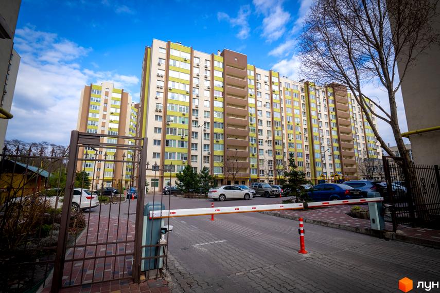 Житловий комплекс Софіївський квартал: багатоповерхові будинки з яскравим фасадом та прибудинкова територія з парковкою та шлагбаумом.