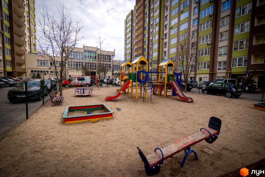 Житловий комплекс Софіївський квартал на вулиці Академіка Шалімова. Дитячий майданчик з гірками, пісочницею та каруселлю на піщаному покритті.