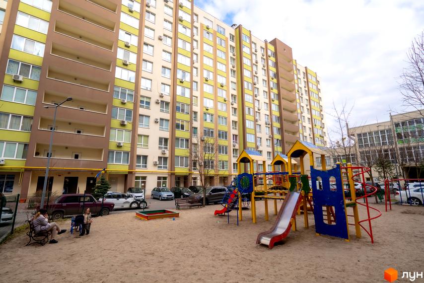 Житловий комплекс Софіївський квартал з фасадом у світло-бежевих та салатових тонах. На прибудинковій території розташований дитячий майданчик з гірками та пісочницею.