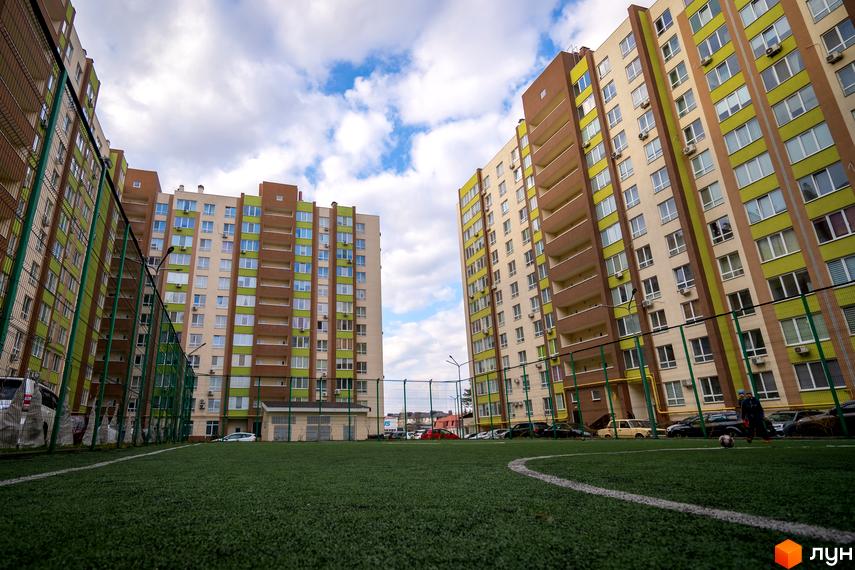 Зображення житлового комплексу Софіївський квартал на вулиці Академіка Шалімова. Вигляд багатоповерхового будинку з вікнами та балконами, зелений газон перед будинком.