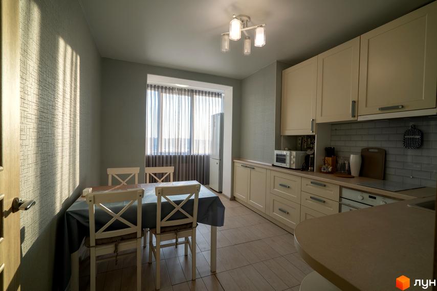 Інтер'єр кухні в Житловому районі Софіївський квартал на вулиці Ак. Шалімова. Обідній стіл з білими стільцями, кухонні меблі світлого кольору.