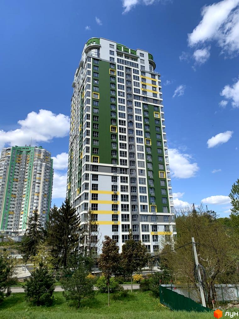 Вигляд житлового комплексу Паркове місто з зеленими та жовтими акцентами. Прибудинкова територія з деревами та газонами.