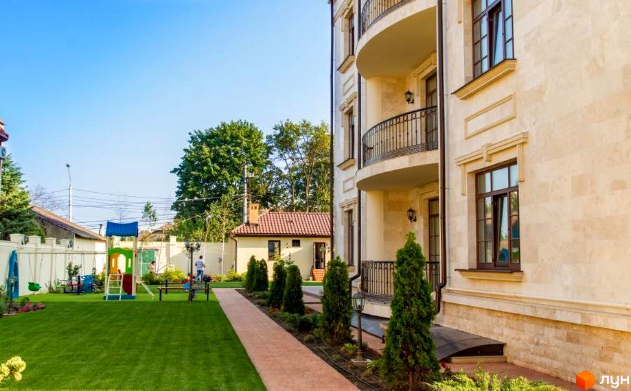 Клубний будинок „Ліон“ з елегантною фасадною обробкою та балконами. Прибудинкова територія з дитячим майданчиком та зеленим газоном.