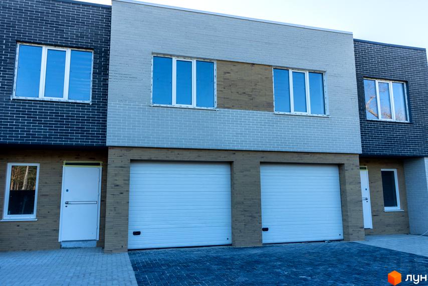 Таунхауси Forest House. Зовнішній вигляд новобудови з цегляним фасадом та гаражними воротами. Прибудинкова територія вимощена плиткою.