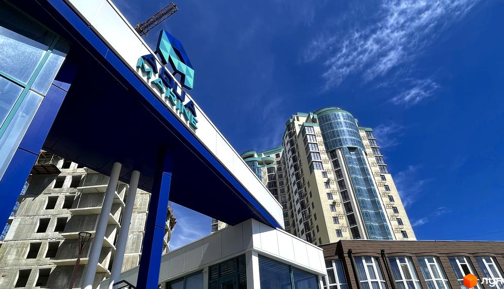 Житловий комплекс Aqua Marine. Сучасна архітектура новобудови з панорамним склінням та блакитним небом на фоні.