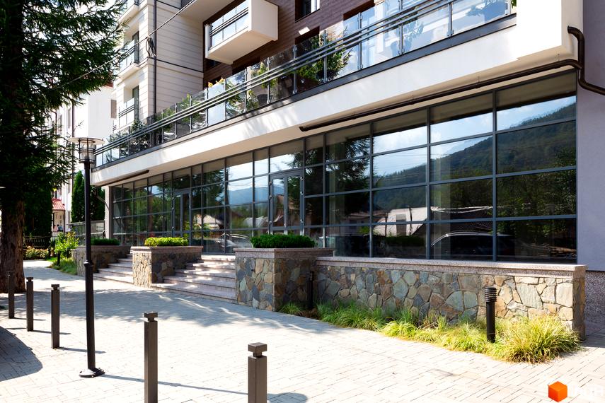 Зовнішній вигляд житлового комплексу Крайобраз з великими вікнами та кам'яною облицовкою. Прибудинкова територія з бруківкою та освітленням.