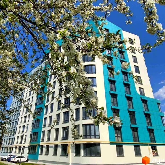 Житловий комплекс Парус Riverside. Біло-блакитна новобудова з великою кількістю вікон, оточена квітучими деревами.