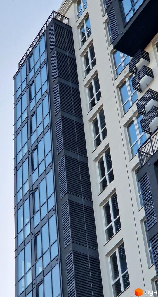 Висотна будівля Житлового комплексу Янтарний з комбінованим фасадом: скляні панелі, світлі стіни та темні вентильовані елементи.