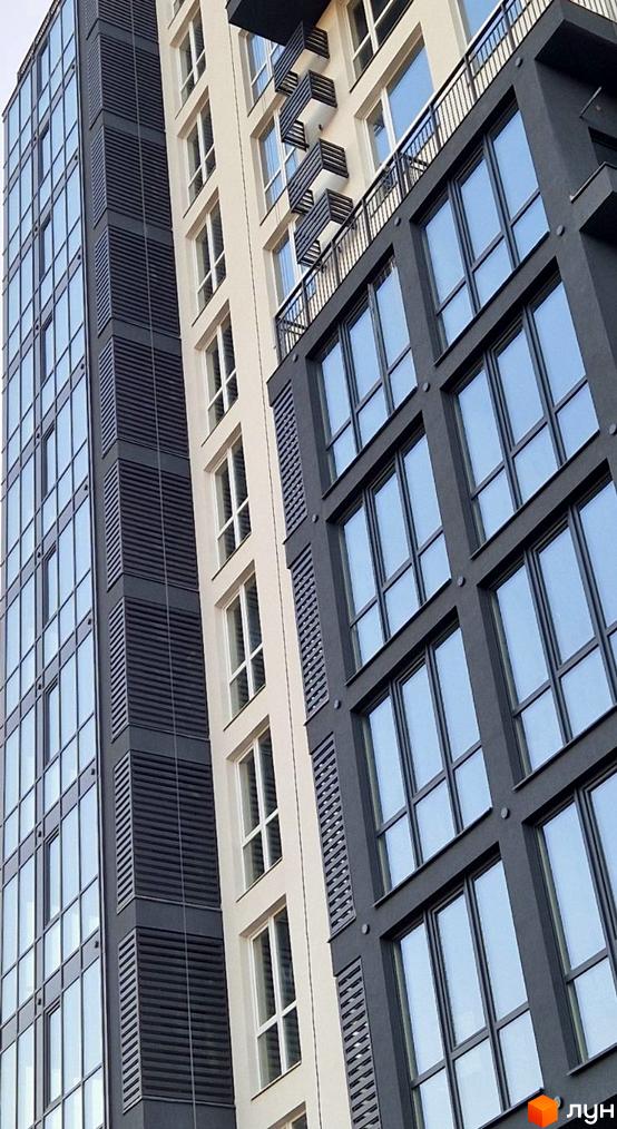 Фасад житлового комплексу Янтарний з панорамними вікнами та балконами. Зовнішній вигляд новобудови з сучасною архітектурою.