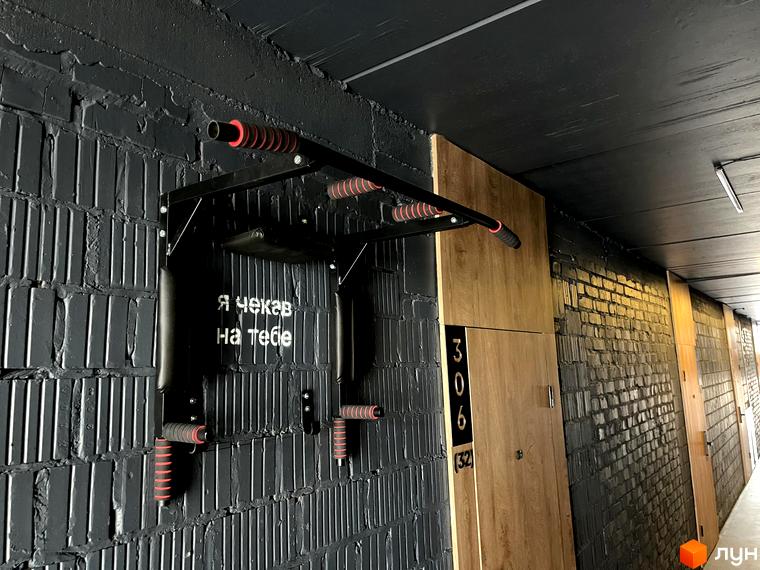 Інтер'єр загального коридору в Coliving EST з чорними цегляними стінами, дерев'яними дверима та турніком для тренувань.