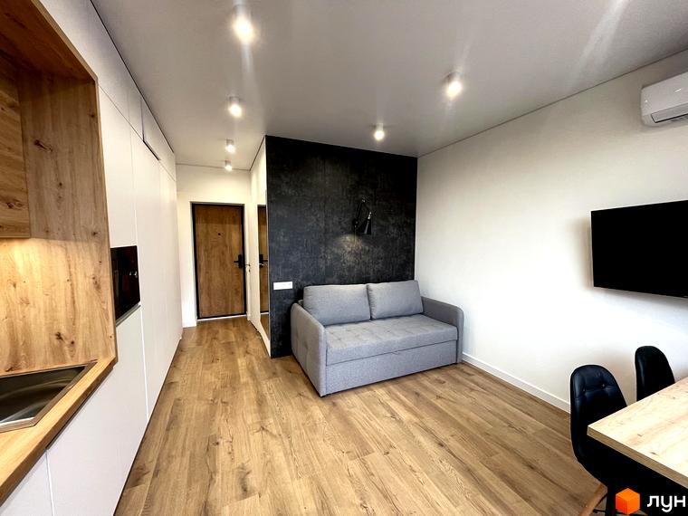 Інтер'єр житлового простору Coliving EST зі світлими стінами та дерев'яною підлогою. Приміщення обладнане зонами кухні, вітальні та їдальні.