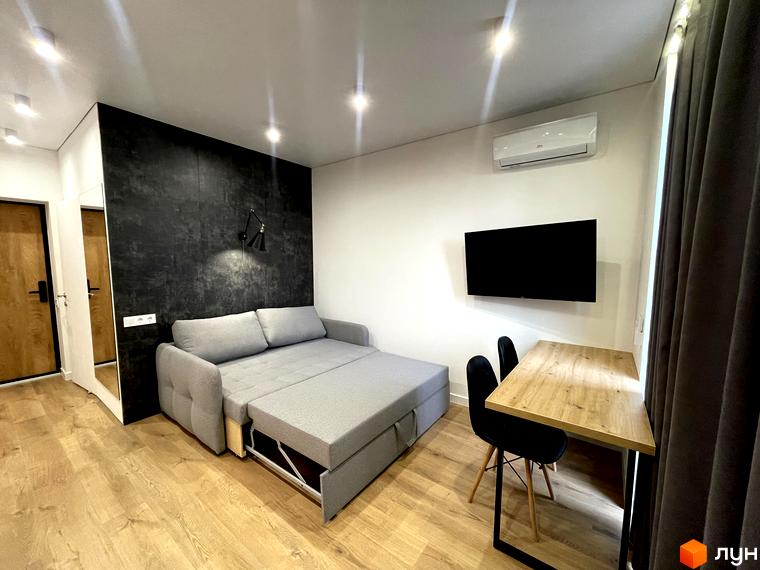 Сучасний інтер'єр студії з розкладним диваном, робочим столом та телевізором. Coliving EST - це комфортне житло для життя та роботи.