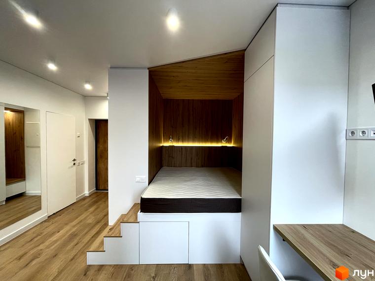 Інтер'єр кімнати в Coliving EST з функціональним ліжком-подіумом, дерев'яними елементами та робочим столом.