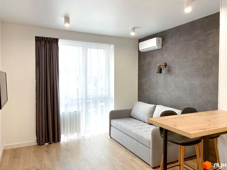 Простора кімната в Coliving EST з функціональним плануванням: світлий інтер'єр, розкладний диван, барна стійка та панорамне вікно.