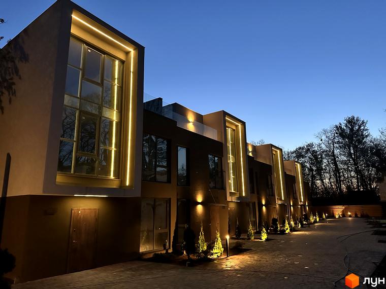 Зовнішній вигляд Elwood Townhouse з підсвічуванням вночі та бруківкою на території. Сучасна архітектура та освітлення створюють затишну атмосферу.