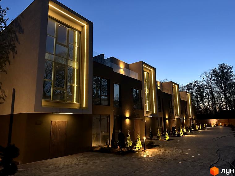 Зовнішній вигляд Elwood Townhouse з підсвічуванням ввечері. На території комплексу розташовані дерева та освітлення.