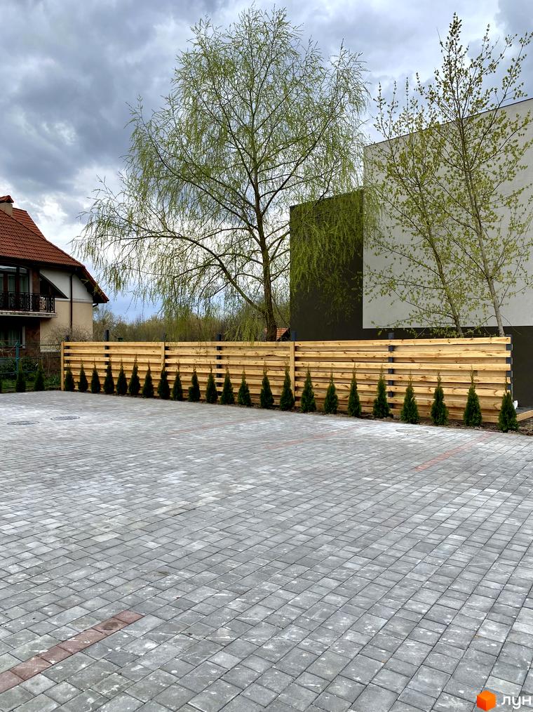 Зовнішній вигляд Elwood Townhouse з дерев'яним парканом та акуратними туями. Прибудинкова територія з бруківкою та зеленими деревами.