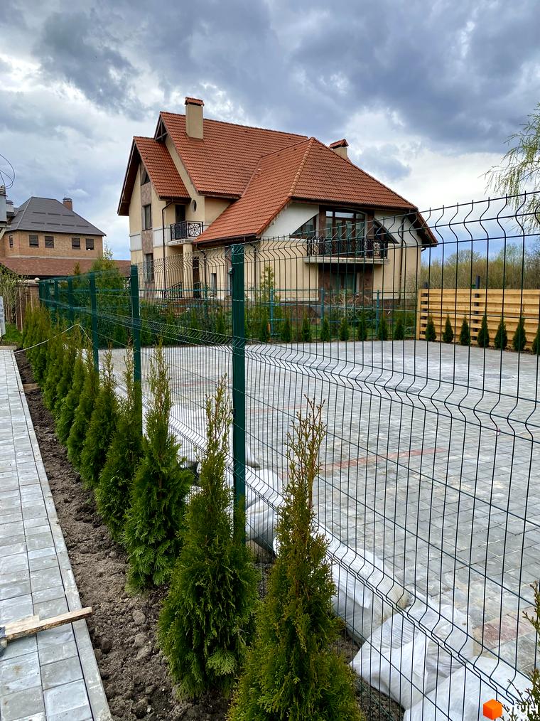 Будинок Elwood Townhouse з червоним черепичним дахом та зеленою огорожею. Поруч висаджені туї та вимощена доріжка з плитки.