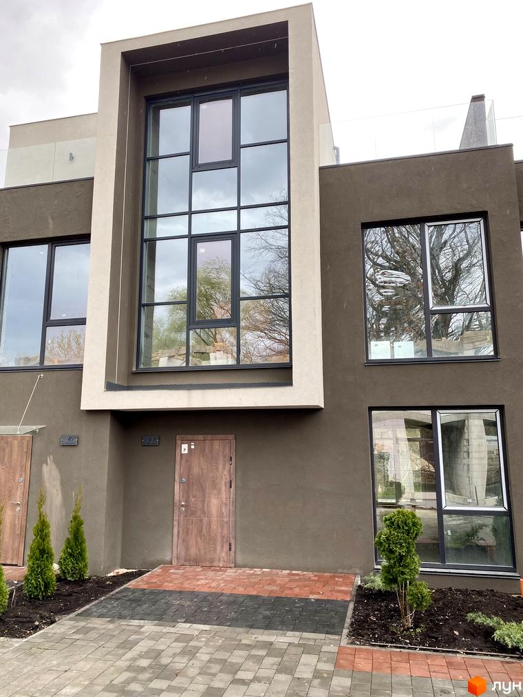 Фасад будинку Elwood Townhouse з великими вікнами та дверима. Поруч висаджені туї та вимощені доріжки.