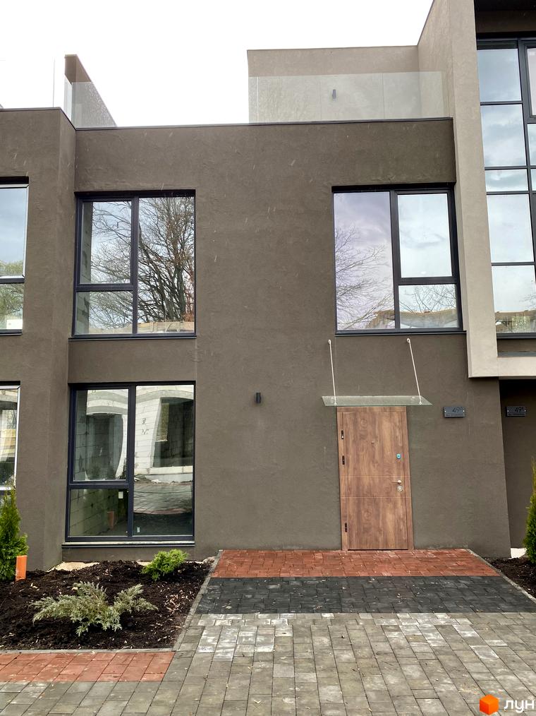 Фасад Elwood Townhouse з великими вікнами та дерев'яними дверима, перед будинком викладена доріжка з плитки та зелені насадження.