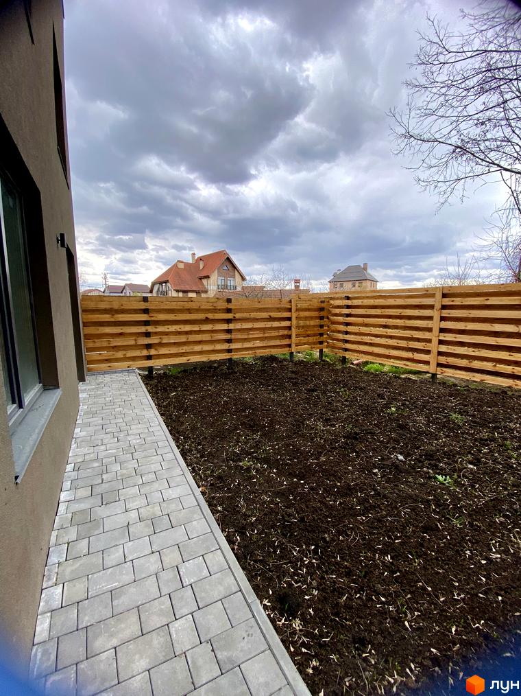Зовнішній вигляд будинку Elwood Townhouse з сірою стіною та вікнами, прибудинкова територія з вимощеною доріжкою та дерев'яним парканом.