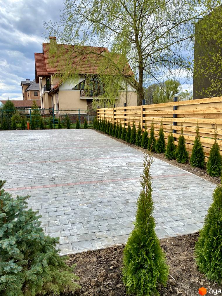 Будинок Elwood Townhouse з червоним дахом та світлим фасадом, поруч вимощена сіра плитка та зелені туї.