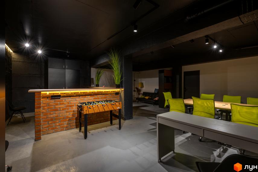 Зона відпочинку та спільних зустрічей у Coliving Akadem з цегляною барною стійкою, настільним футболом та обідньою зоною.