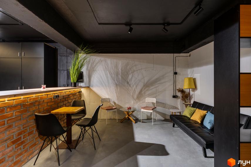 Інтер'єр коворкінгу в Coliving Akadem з цегляною стіною, столом та стільцями, диваном та лампою.