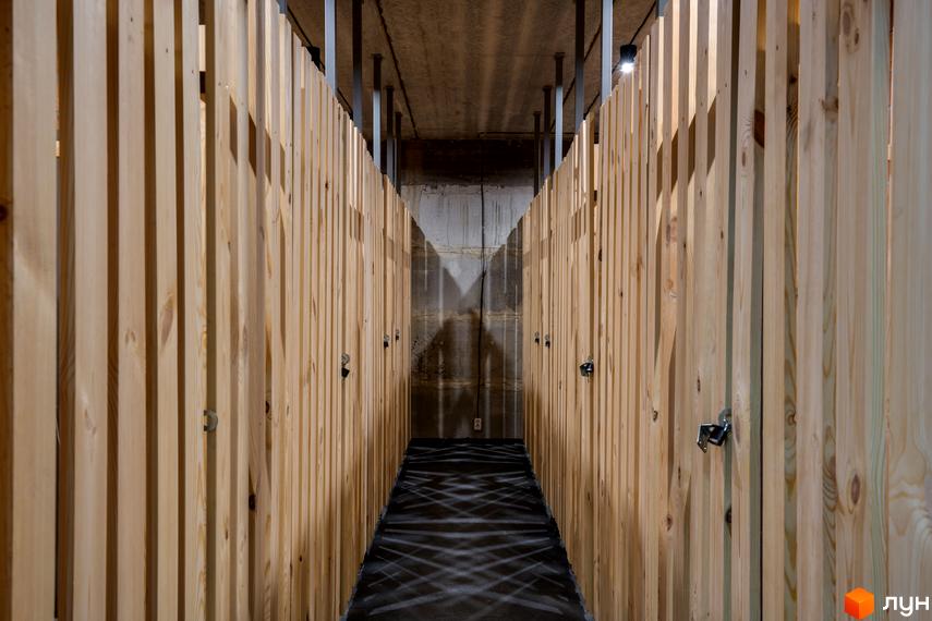 Функціональний простір для зберігання речей у Coliving Akadem, представлений коридором з дерев'яними боксами. Зручні комори для мешканців.