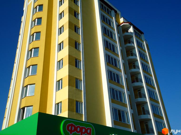 Зовнішній вигляд новобудови ЖК Гостомельський квартал. Багатоповерховий будинок з жовтим фасадом та балконами.