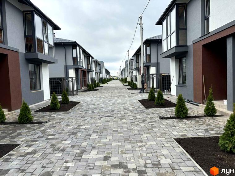 Котеджне містечко Beverly Hills Residence з сірими фасадами та великими вікнами, вимощена алея з зеленими насадженнями.