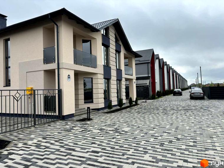 Котеджне містечко КМ Beverly Hills Residence: фасади будинків з панорамними вікнами та скляними балконами, вимощені доріжки та припарковані автомобілі.