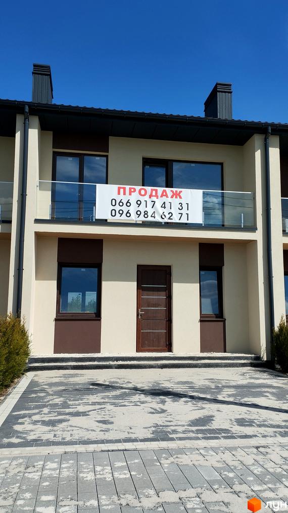 Зовнішній вигляд фасаду будинку з балконом та вивіскою 