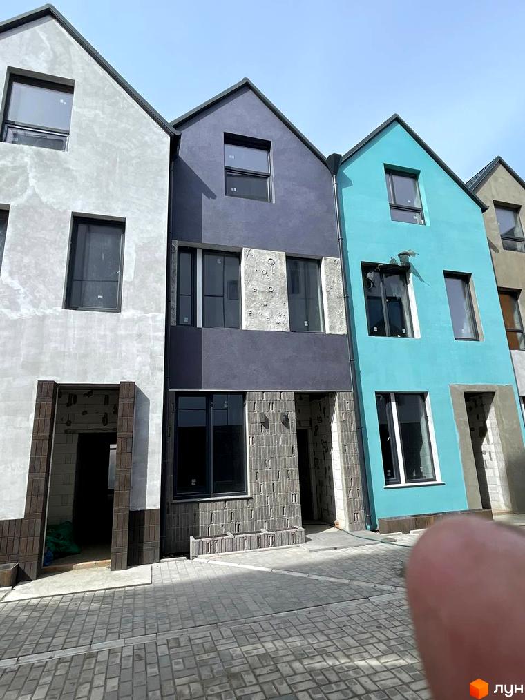 Котеджне містечко KADENYUK homes з фасадами різних кольорів: сірим, синім та бірюзовим. Перед будинками розташована бруківка.