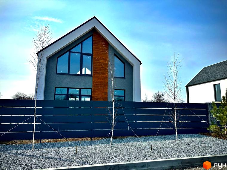 Котеджне містечко КМ Fill House з сірою штукатуркою та великими вікнами, огороджене темною парканом та засипане гравієм.