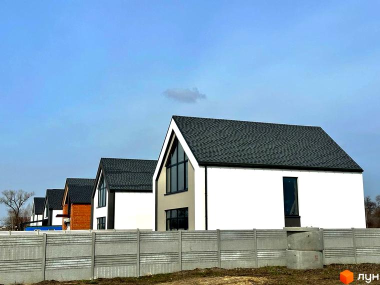 Котеджне містечко КМ Fill House. Сучасні білі будинки з темними дахами та великими вікнами, огороджені бетонним парканом.