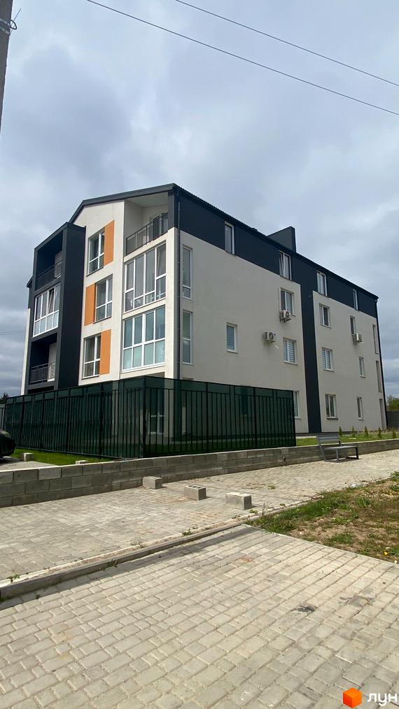 Зовнішній вигляд житлового комплексу Club House з білими та чорними фасадами, великими вікнами та балконами. Прибудинкова територія з бруківкою та огорожею.